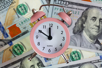 pink quartz alarm clock isolated on 100 dollar backgrounde