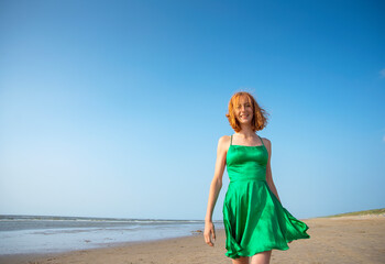 Fototapeta na wymiar fröhliches Mädchen in grünem Kleid am Strand