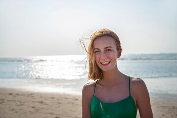 fröhliches Mädchen in grünem Kleid am Strand