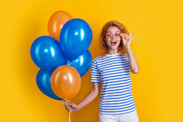 Fototapeta na wymiar amazed girl with birthday balloon in sunglasses. happy birthday girl hold party balloons in studio