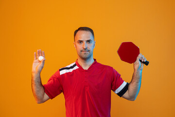 Man plays table tennis on yellow studio background. Professional player plays ping pong. Horizontal...