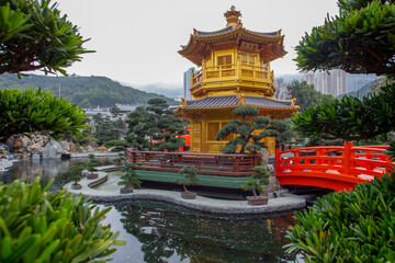 Fantastic podocarp large-leaved bonsai trees  and central golden pagoda surrounded water pond -...