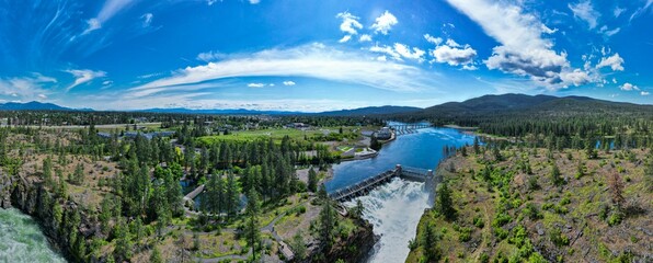 Arial view of Post Falls Dam surrounded by trees with blue sky in the background