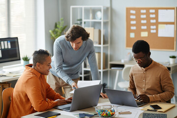 Portrait of creative business team working together in office, focus on young man consulting with colleagues