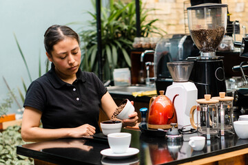 Coffee shop staff, separating portions of coffee. Young latina and brunette woman.