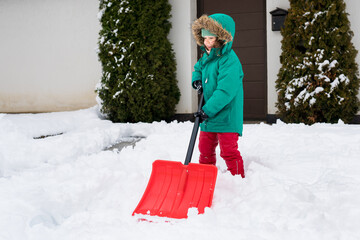 Child clearing sidewalks and shoveling snow. Girl removaling snow with  shovel. Little helper for...