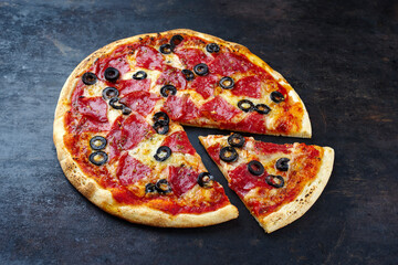 Traditional Italian pizza al salame with salami, mozzarella and olives served as a close-up on an old rustic board with text free space