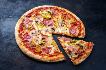 Traditional Italian pizza prosciutto e funghi with ham, mushrooms and mozzarella served as close-up on an old rustic board with text free space