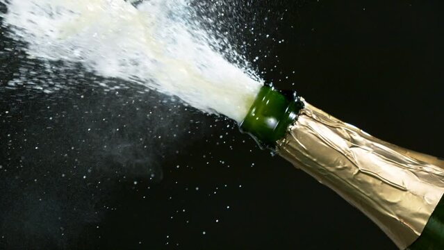 Super slow motion of Champagne explosion with flying cork closure, neon colors, opening champagne bottle closeup.