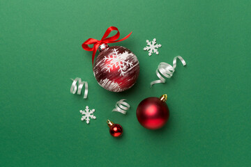 Christmas ball toys and confetti on color background, top view