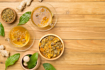 Herbal tea with ingredients on wooden background, top view