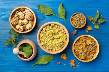 Different herbs in bowls on wooden background, top view