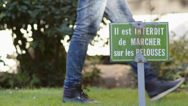 Femme qui marche sur une pelouse interdite avec un panneau