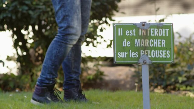 Femme qui marche sur une pelouse interdite avec un panneau