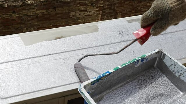 a man paints with anti-corrosion paint the metal structure, air conditioner.