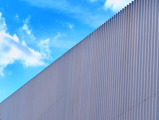 Fototapeta na wymiar Blue sky clouds over diagonal fence backdrop