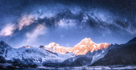 Milky Way arch over snowy mountains at starry night in winter. Landscape with snow covered high rocks, blue sky with stars in Nepal. Bright arched milky way in Himalayas. Space background. Nature - obrazy, fototapety, plakaty
