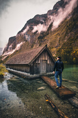 Fototapeta na wymiar Man standing at Boathouse close to Obersee Lake in Berchtesgaden Bavaria in Autumn
