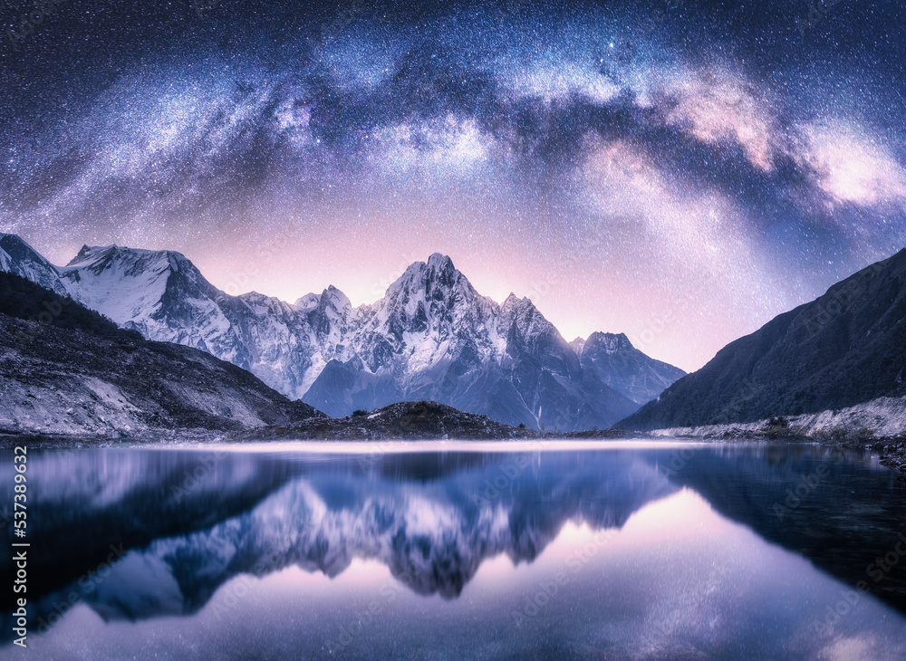 Wall mural milky way arch over snowy mountains and lake at night. landscape with snow covered high rocks, viole
