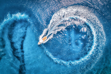 Aerial view of the speed boat in transparent blue water at sunset in summer. Top view from drone of fast floating yacht in mediterranean sea. Tropical colorful landscape with motorboat. Extreme