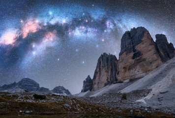 Milky Way arch over mountain peaks at night in summer. Beautiful landscape with blue sky with...