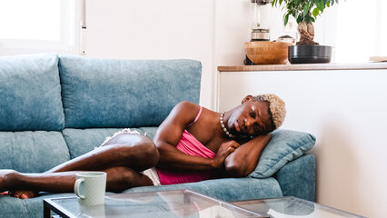 Sad and frustrated transgender person lies on the sofa - obrazy, fototapety, plakaty