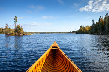 Wooden canoe on a blue Boundary Waters lake with a small island on an autumn morning - Powered by Adobe