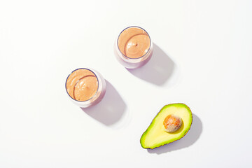 Two glasses with avocado chocolate smoothie with ingredients on white background. Top view, flat lay