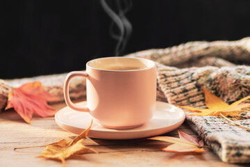 Coffee cup, autumn leaves and knitted sweater on wooden table. Fall concept
