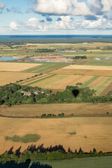Obraz premium Rural landscape from a hot air balloon. Lithuanian agricultural fields in the early morning. Vertical photo