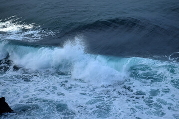 Obraz premium The waves crashing in the ocean, with a bluish tint at Drini Beach, Gunungkidul, Yogyakarta