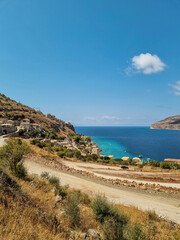 view of Limeni village with fishing boats in turquoise waters and the stone buildings as a background in Mani, Greece.