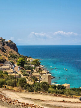 view of Limeni village with fishing boats in turquoise waters and the stone buildings as a background in Mani, Greece.