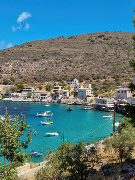 view of Limeni village with fishing boats in turquoise waters and the stone buildings as a background in Mani, Greece.