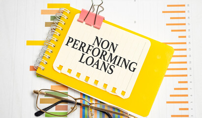 NON PERFORMING LOANS words on yellow notepad and charts - obrazy, fototapety, plakaty
