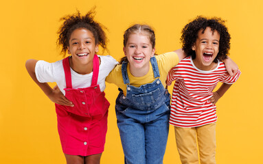 Group of cheerful happy multinational children on  yellow background