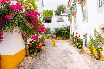 The historic Portuguese village of Obidos and narrow streets of cobblestone with traditional colored houses with beautiful flowers. Obidos, Portugal