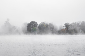 Heavy fog on Ottawa river obscuring forested island in autumn, morning, nobody