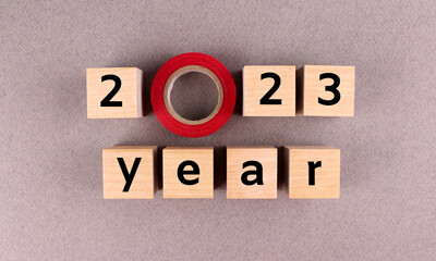 Wooden cubes with numbers and letters with red electrical tape lined with inscription 2023 year on a gray background
