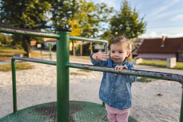 One girl small caucasian child female toddler 18 months old in park play in day on speedy spinner merry-go-round turnabout childhood and growing up concept copy space