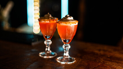 Orange drink in a cup with whipped cream on black wooden background
