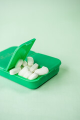 Some pills in a green pillbox on green background