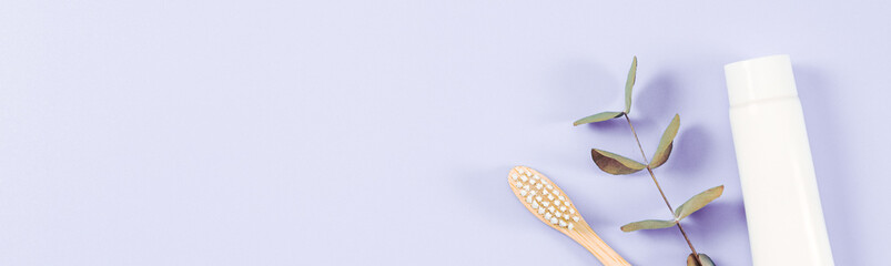 Toothpaste and bamboo toothbrush on soft lilac.