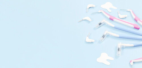 A set of small toothbrushes and paper teeth on soft blue.