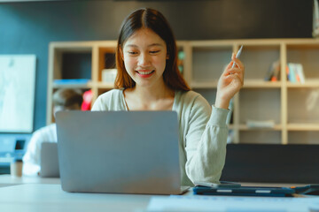 Using laptop, Beautiful young Asian businesswoman working at workspace.