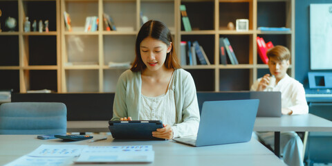 Using laptop, Beautiful young Asian businesswoman working at workspace.