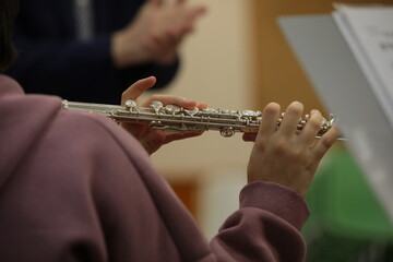 Student playing flute at lesson with teacher in classroom.Background image of youth leisure and...