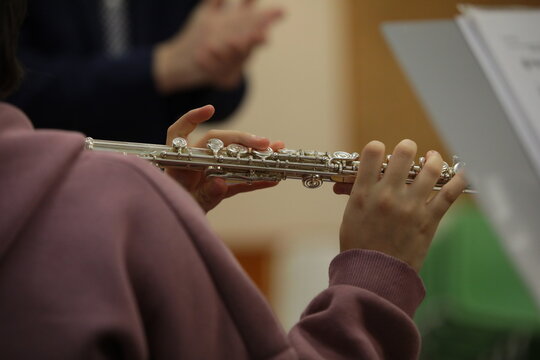 Student playing flute at lesson with teacher in classroom.Background image of youth leisure and development