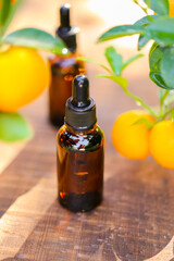 Citrus oil.tangerine essential oil.Natural organic pure oil. brown bottles with oil on a brown wood background and tangerines with green leaves.