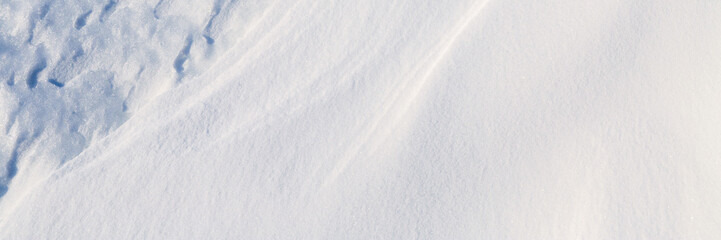 Fototapeta na wymiar Beautiful winter background with snowy ground. Natural snow texture. Wind sculpted patterns on snow surface. Wide panoramic texture for background and design.